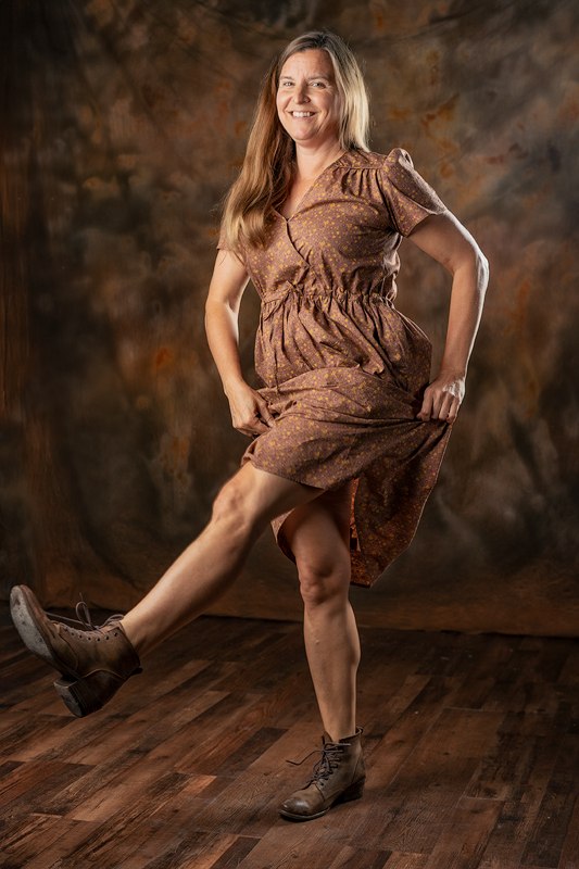 smiling woman dancing in old-fashioned brown dress and boots